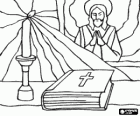 The Bible and a lit candle on the altar with an image of Jesus in the background