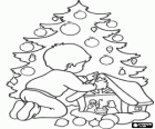 Child placing the star in the nativity scene in front of Christmas tree