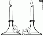 Two lighted candles in candelabra adorned with holly leaves